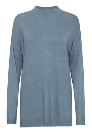 Šviesiai mėlynas per didelis megztinis su aukštu kaklu, ilgomis rankovėmis ir raukšlėmis rankogaliuose. Pagamintas iš minkštos, tekstūruotos medžiagos.