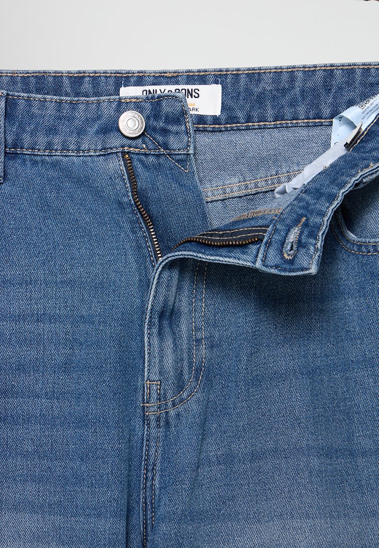Blaue Jeans aus Denim mit Reißverschluss und Druckknopfverschluss, ausgestattet mit klassischem Fünf-Taschen-Design und verblasster Textur an den Oberschenkeln.