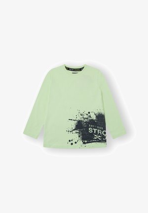 Camiseta de manga larga en algodón verde claro con estampado de salpicaduras negras y texto "ESTD 1953 STRONG". Cuello redondo clásico y textura suave.