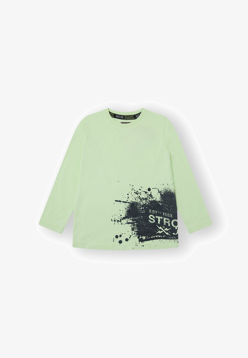 Camiseta de manga larga en algodón verde claro con estampado de salpicaduras negras y texto "ESTD 1953 STRONG". Cuello redondo clásico y textura suave.