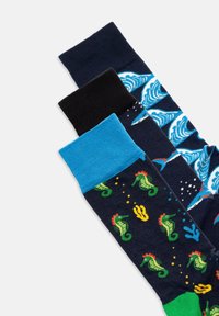 Set van drie sokken: marineblauw met zeepaardjes, blauw golfpatroon, effen zwart. Elke sok heeft unieke gekleurde ribbels; de texturen variëren per ontwerp.