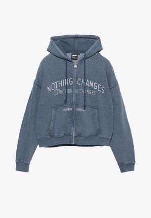 Blå cropped zip-up hoodie lavet af bomuldsblanding. Har en kengurulomme, snore og et fronttekstdesign i kontrastfarve hvid.