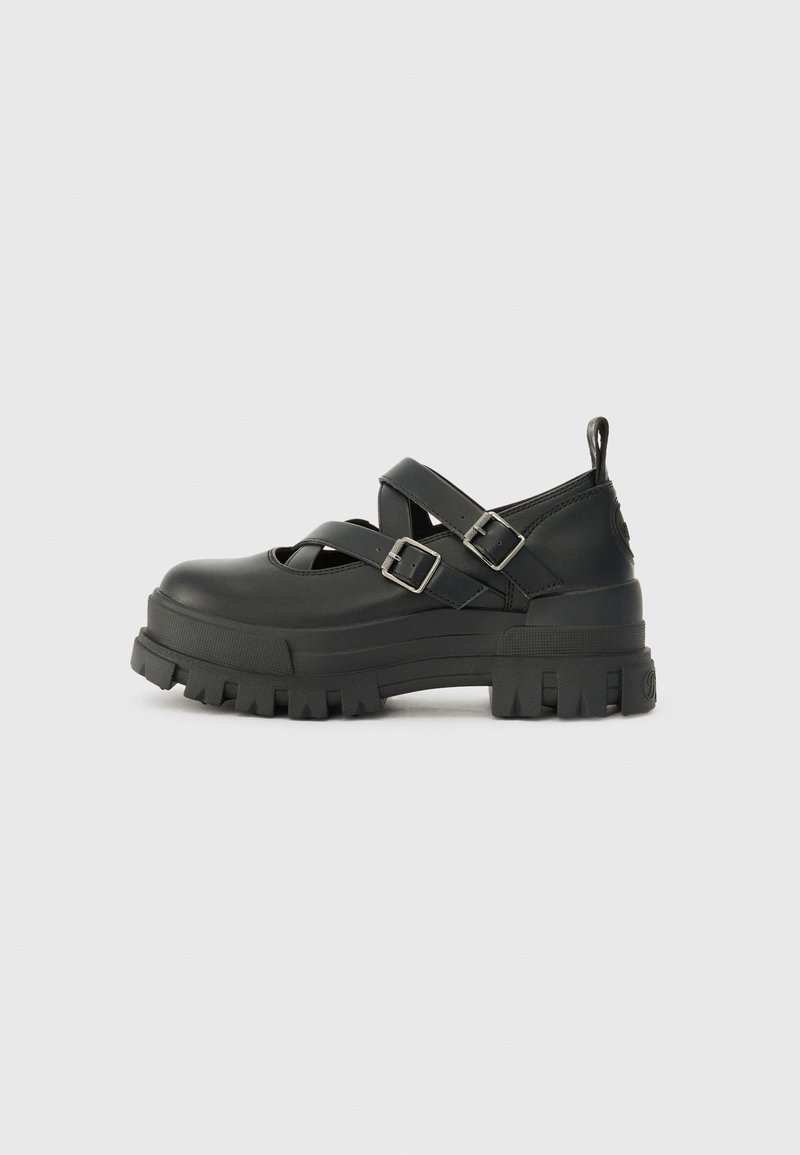 Black platform shoes with a chunky sole, featuring cross straps and buckles. Made of smooth material with a matte finish.