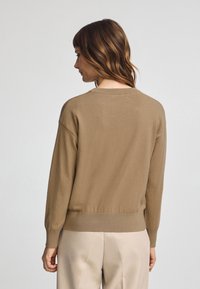 Brauner Strickpullover mit langen Ärmeln und rundem Halsausschnitt, mit gerippten Bündchen und Saum, glatter Textur und lockerer Passform.