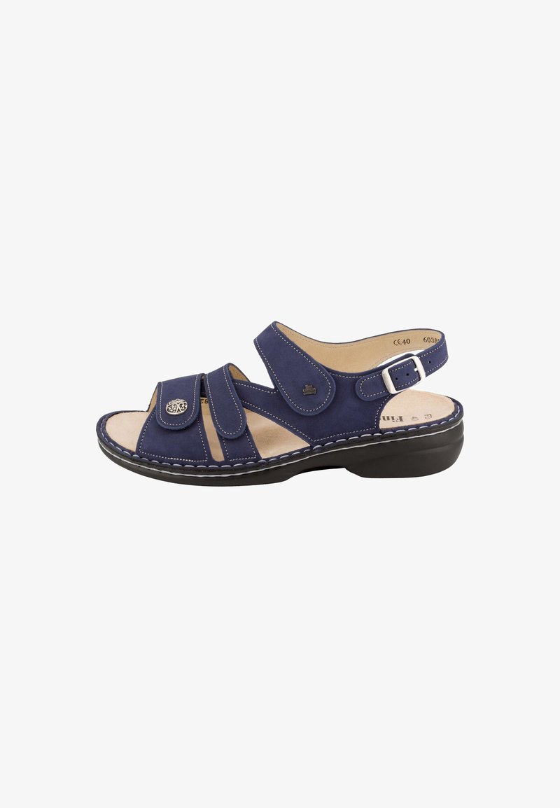 Sandale bleu marine à bout ouvert avec lanières réglables, semelle intérieure beige rembourrée, semelle noire basse et boucle argentée sur la bride de cheville.