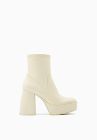 Bottine beige à plateforme montant à la cheville avec un talon épais en bloc et une finition en cuir lisse, vue de côté.