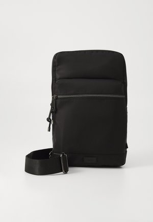 Melnas neilona crossbody soma ar rāvējslēdzēja galveno nodalījumu, mīkstinātu priekšējo paneli un regulējamu siksnu. Minimalistisks dizains ar gludu apdari.