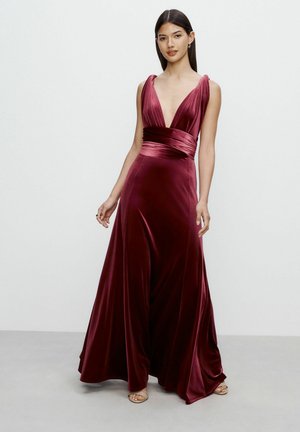 Bordó bársonydressz mély V-kivágással, széles vállpántokkal és megkötős derékrésszel. Elegánsan leomlik a földre.
