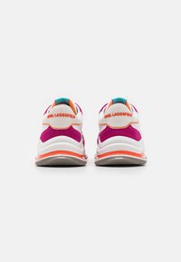 Pari valkoisia lenkkikenkiä, joissa on vaaleanpunaisia mokkaaksentteja ja oransseja yksityiskohtia, nähdään takaa. Kenkien kantapäissä on "Karl Lagerfeld" -logo.