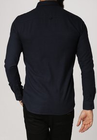 Navy blauwe langslifestyle met lange mouwen, gemaakt van een katoenmix, met een subtiele textuur, knoopmanchetten en een rugdetail.