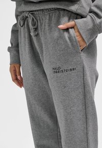 Graue Jogginghosen aus weichem Stoff mit elastischem Bund und Kordelzug. Verfügt über eine Seitentasche und "HALO 196819721981" auf dem Bein aufgedruckt.