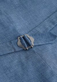Tissu tissé bleu avec une boucle en métal argenté fixant une ceinture en tissu assorti.