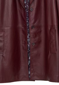 Giacca di pelle rosso scuro con tre bottoni neri e due tasche frontali, che lascia parzialmente intravedere una fodera interna fantasia.