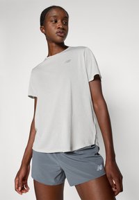 T-shirt d'entraînement à manches courtes gris clair en tissu texturé avec un logo subtil, associé à un short gris foncé arborant un logo.