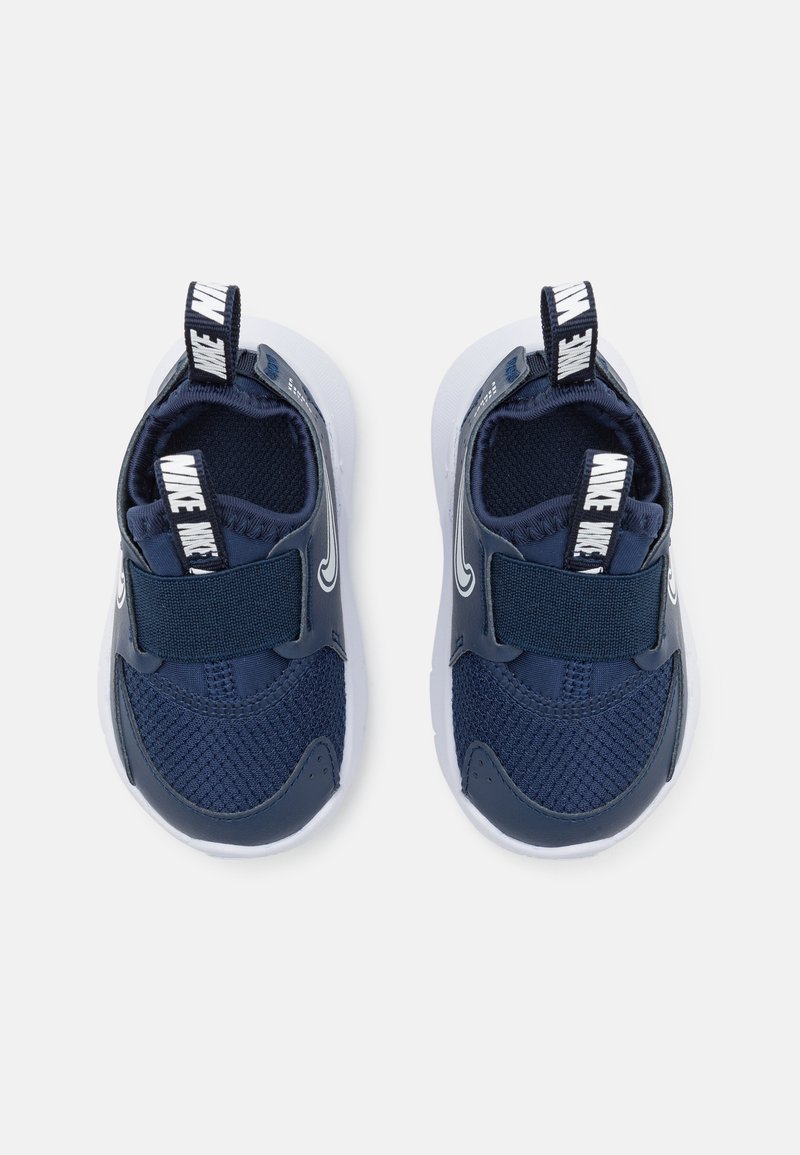 Scarpe da ginnastica blu navy con una tomaia in rete traspirante, cinturino elasticizzato e suola in gomma bianca. Presentano un manico per un facile indossamento.