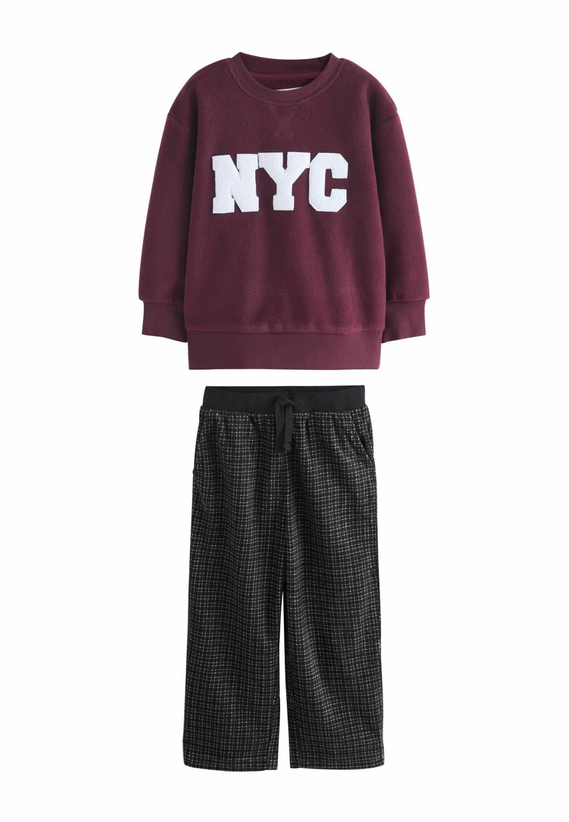 Burgundivärgad sweatshirt med vit "NYC" text, kombinerad med löst sittande svarta rutiga byxor med elastisk midja och fickor.