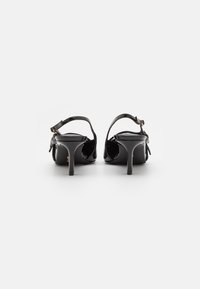 Sandali con tacco in vernice nera, con apertura sul retro, tacchi a stiletto slanciati e cinturini alla caviglia regolabili con hardware color oro.