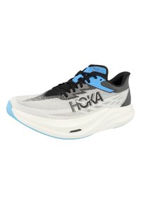 Baskets de course blanches et noires avec des accents bleus, semelle épaisse et rembourrée, lacets noirs et logo "HOKA" sur le côté et la languette.