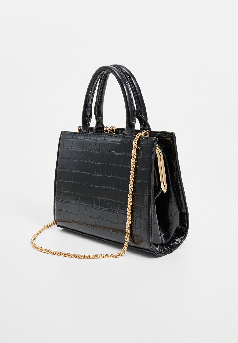 Sac à main noir en simili-crocodile avec une forme structurée, doté de deux poignées courtes et d'une bandoulière en chaîne dorée.