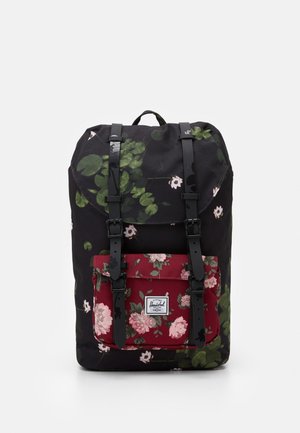Rygsæk med sorte og røde blomsterprint, to sorte stropper med spænder og frontlomme med mærkeetiket.