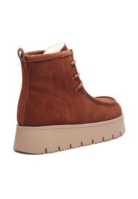 Rudos spalvos zomšos aulinukas su apvalia nosimi, priekiniu užtraukiamu raišteliu, smėlio spalvos gumine platformos sole ir imitacijos kailio apdaila aplink apykaklę.