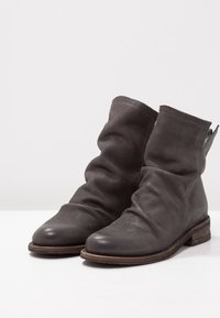 Bottines en cuir gris avec un design décontracté, des perforations texturées, des bouts ronds et un talon en bois empilé.