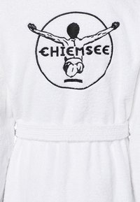 Weißer Frottee-Bademantel mit Gürtel, versehen mit einem runden schwarzen Logo, das eine Figur mit ausgestreckten Armen und dem Text "CHIEMSEE" zeigt.