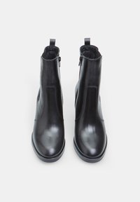 Botas de cuero negro hasta el tobillo con un acabado suave, puntera redondeada, cierres de cremallera en el lateral y tiradores en la parte posterior para facilitar su colocación.
