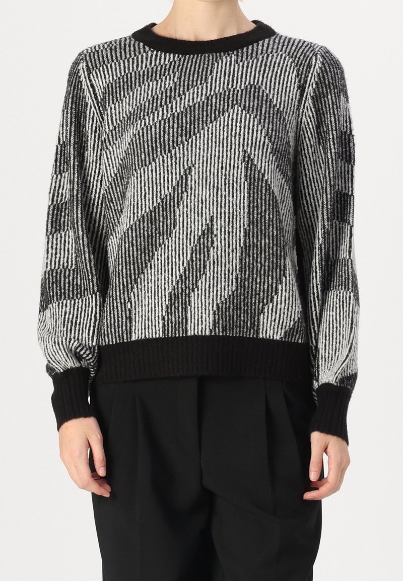 Svartvit tröja med randigt mönster, stickade muddar och nederkant samt en avslappnad passform. Tillverkad av texturerat stickat material.