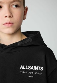 Sudadera de algodón negra con capucha, featuring un cordón, textura acanalada y un estampado de logotipo frontal en blanco con texto japonés.
