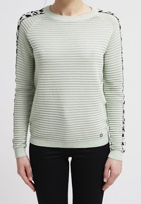 Hellgrüner, gerippter Pullover mit schwarzen, gemusterten Akzenten an den Schultern. Verfügt über einen Rundhalsausschnitt und enganliegende Bündchen. Strukturierter Stoff.