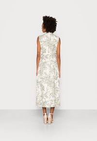 Abito midi senza maniche in crema chiaro con stampa floreale verde, vita cinchata e silhouette ad A, abbinato a sandali con tacco blocco beige.