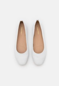 White ballet flats with a smooth leather exterior, rounded toe, and a simple slip-on design. Interior features a beige insole with perforations.
