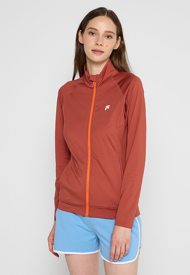 Chaqueta deportiva tipo sudadera en burdeos con cremallera naranja, de mangas largas y diseño ajustado. Logo en el lado izquierdo del pecho. Tejido liso y elástico.