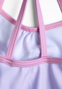 Top da bagno viola con spalline rosa, con tessuto arricciato al centro. Texture liscia e dettagli di cucitura a contrasto.