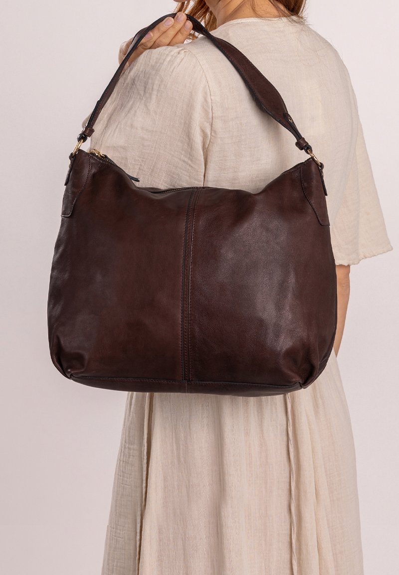 Grande borsa a spalla in pelle marrone con forma curva, texture liscia e tracolla regolabile con dettagli in metallo dorato.