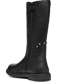Bottes noires montantes en simili cuir avec une fermeture éclair sur le côté, des accents festonnés et des détails en clous argentés sur le côté extérieur. Talon bas.