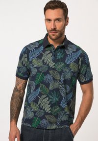 Polo a maniche corte in cotone blu navy, con un motivo a foglie multicolore con accenti verdi, blu e gialli, e colletto a punta.