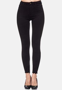 Jean skinny noir taille haute, avec des détails effilochés aux chevilles et une fermeture à bouton. Fabriqué en denim extensible.