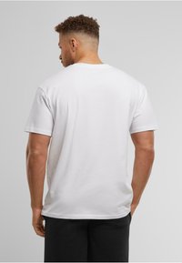 White cotton t-shirt with a crew neckline and short sleeves. The back shows a simple, smooth fabric and relaxed fit. No graphics or patterns.