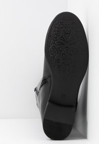 Botte en cuir noir vue du côté de la semelle, montrant un motif décoratif en relief sur la semelle et la taille 37 près du talon.