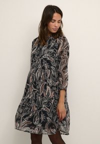 Black and pink paisley patterned dress with three-quarter sleeves, a buttoned front, and a loose fit that falls above the knees.
