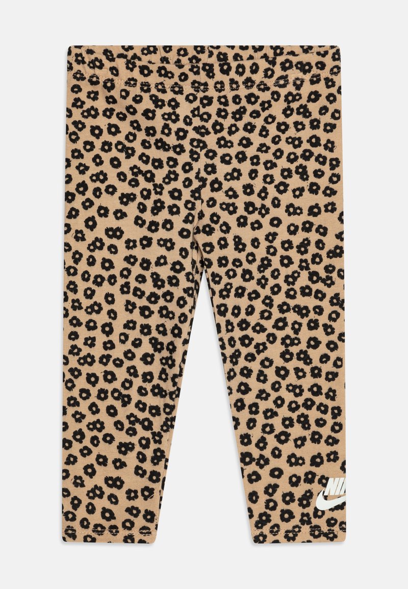 Beige Leggings mit einem schwarzen Blumenmuster, aus weichem Stoff, elastischem Bund und einem weißen Nike-Logo unten rechts.