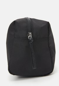 Zwarte stoffen tas met een rechthoekige vorm. Kenmerken zijn een bovenste rits, een gestructureerd oppervlak en een geknoopte ritssluiting voor gemakkelijk gebruik.