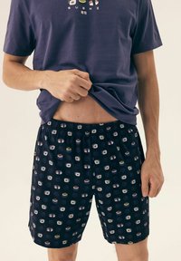 Navy blue cotton shorts with a sushi pattern in various colors. Elastic waistband and relaxed fit. Paired with a purple T-shirt.
