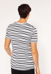 Grå t-shirt med rund hals och svarta horisontella ränder, korta ärmar och normal passform, med en mjuk bomullstextur.