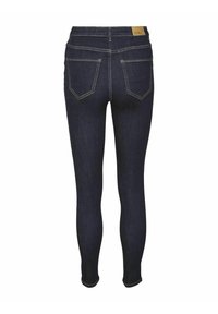 Uskežene traperice tamnoplave boje, sa visokim pojasom, stražnjim džepovima s zakrivljenim šavom i kontrastnim šivanjem.