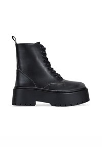 Botas de tobillo de cuero negro con puntera redondeada, cierre de cordones en la parte delantera y suela de plataforma gruesa. Cuenta con un tirador y acentos de costura texturizada.