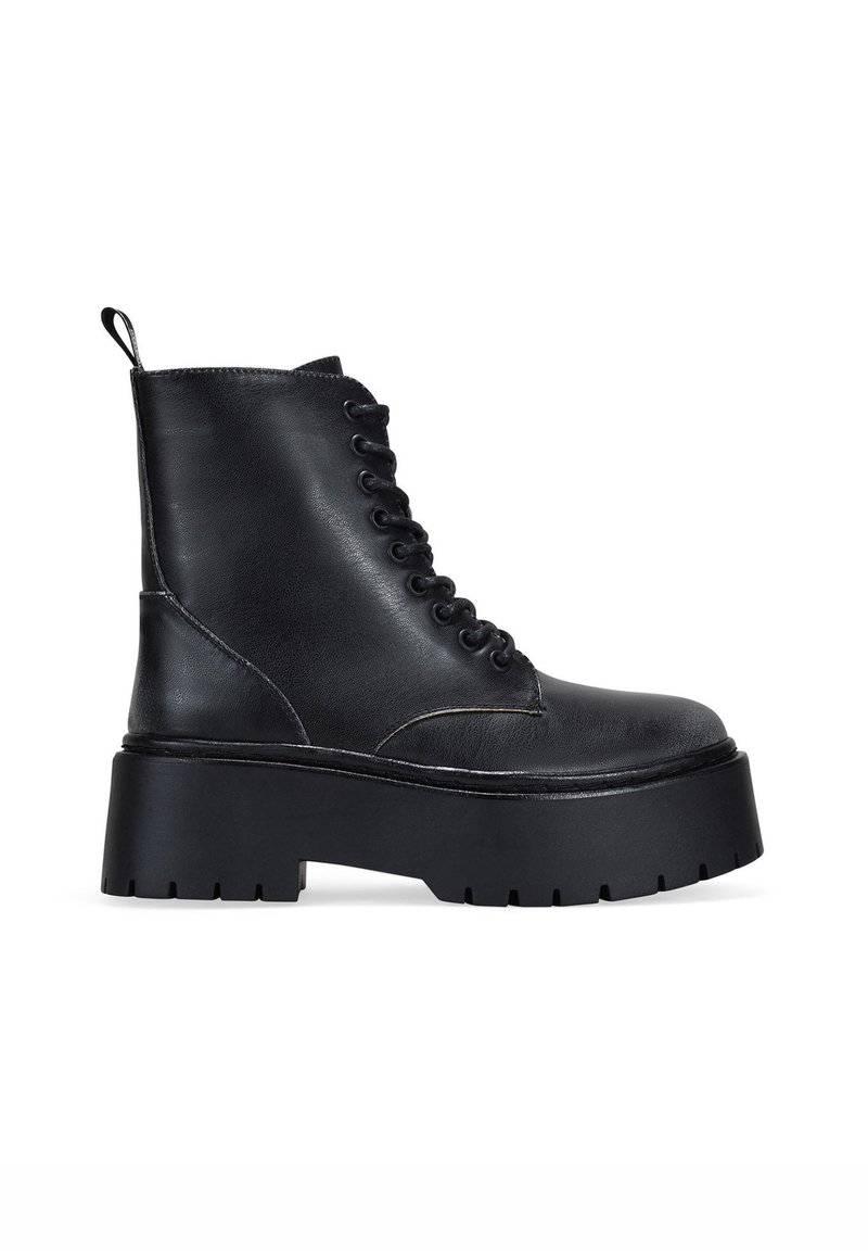 Botas de tobillo de cuero negro con puntera redondeada, cierre de cordones en la parte delantera y suela de plataforma gruesa. Cuenta con un tirador y acentos de costura texturizada.