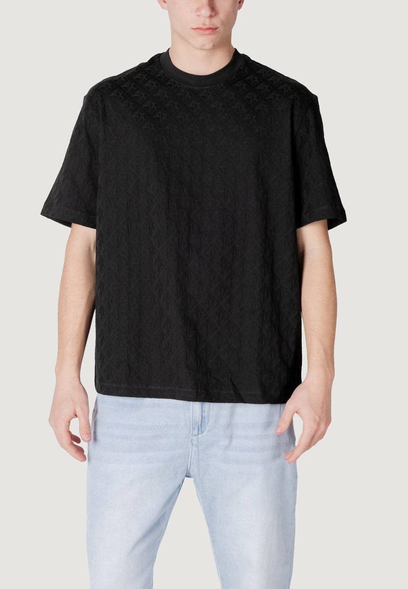 T-shirt nera a maniche corte con un motivo a diamante strutturato, scollo rotondo e vestibilità comoda, abbinata a jeans in denim azzurro chiaro.